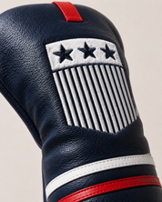 Close-up detail of the navy USA driver headcover showing pebbled leather texture, stitching, and embroidered crest details. The image highlights the white embroidered stars and vertical stripe design, red top tab, and red and white leather bands for a premium handcrafted product feel.
